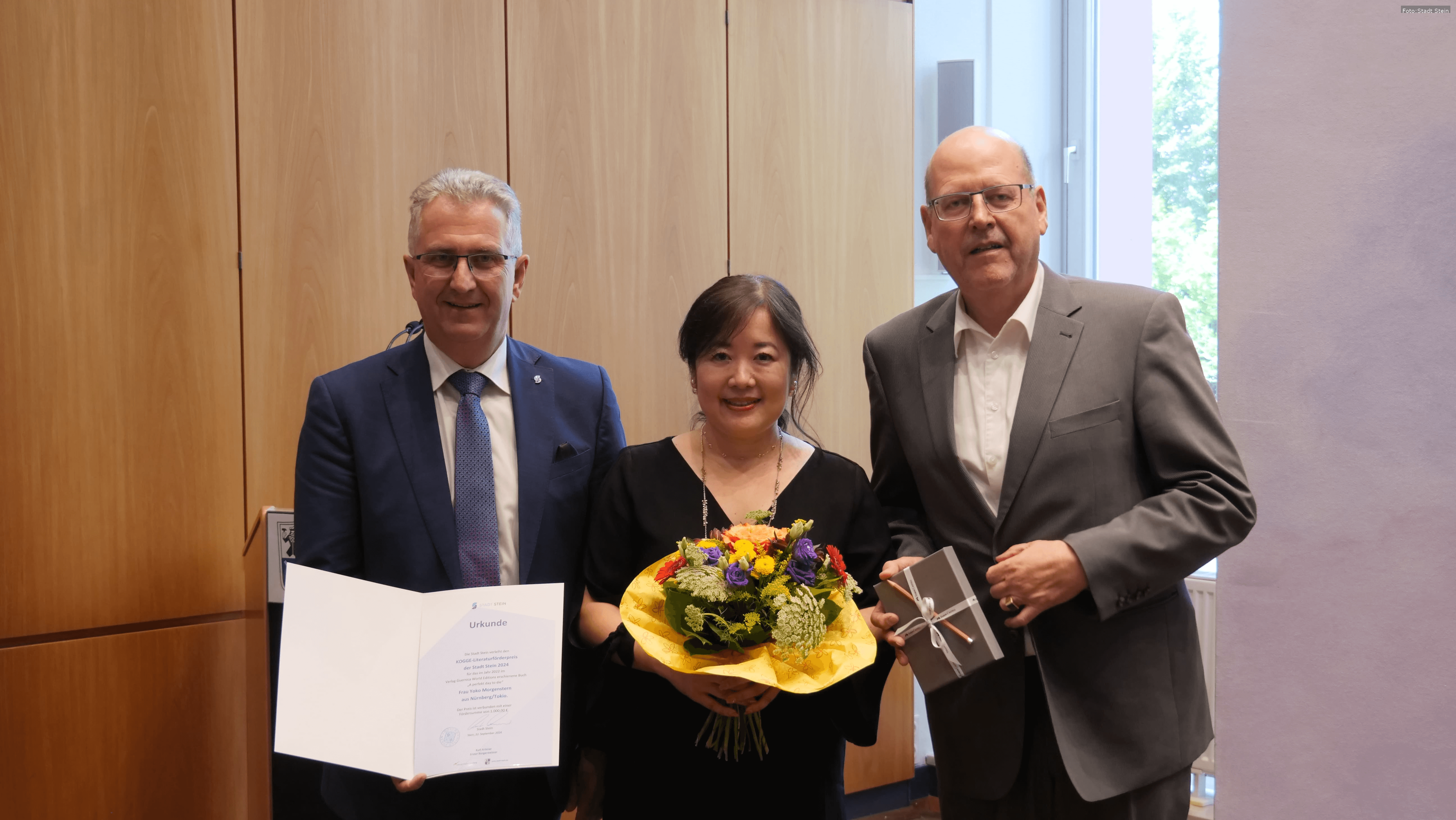 Yoko Morgenstern erhält den Kogge-Literaturförderpreis in Stein. Bürgermeister Kurt Krömer und Uli Rothfuss gratulieren der Autorin.